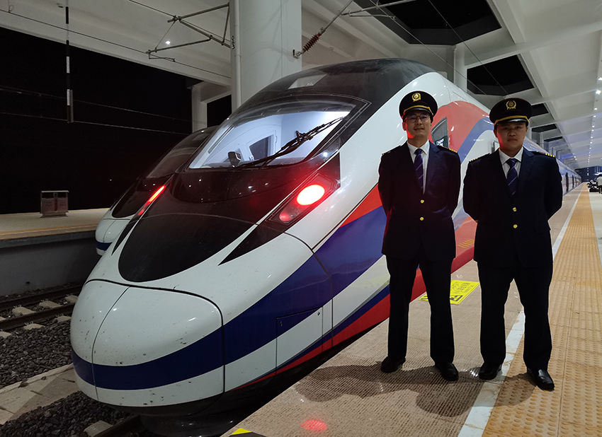 劉銀能（右一）與中國師父鄔俊鴻在動車組前合影。受訪者供圖